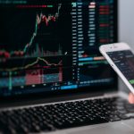 Trading Chart auf einem Laptop mit Smartphone