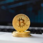 Bitcoin Münze steht auf einem Laptop