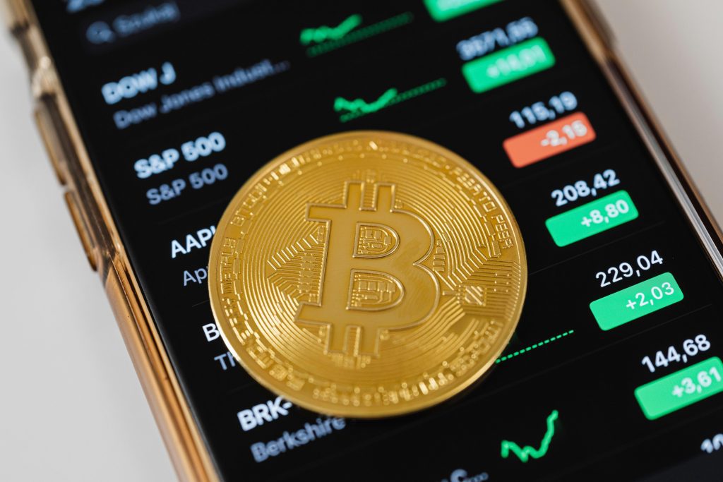Bitcoin Münze liegt auf Smartphone mit Kursen wie dem S&P 500