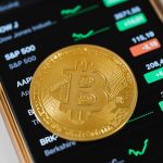 Bitcoin Münze liegt auf Smartphone mit Kursen wie dem S&P 500