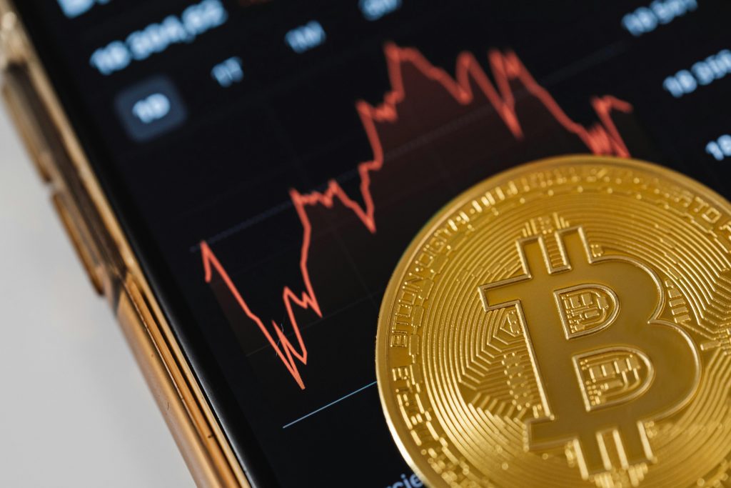 Bitcoin Kurs fällt auf Smartphone mit BTC Münze davor